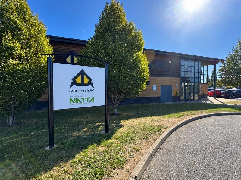 The Farnham RUFC sign in front of the rugby club's clubhouse on a sunny day